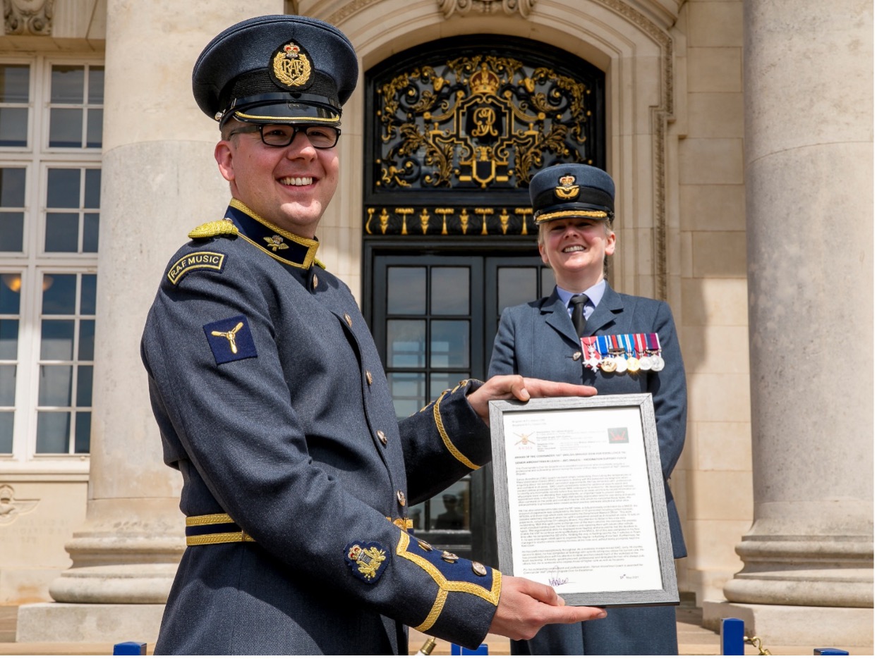 Personnel holds up the framed Coin for Excellence. 